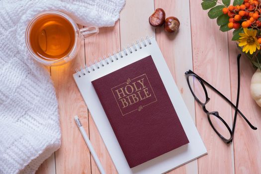 Holy bible and autumn cozy top view on wooden background. Bible study autumn concept.