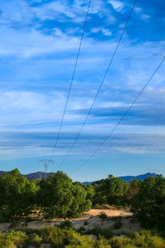 Power lines tower under blue sky in the countryside in Spain