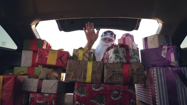 santa claus delivering gifts. gifts from santa. delivery service. deliveryman loads boxes. gift boxes in car. beautifully wrapped parcels. view from inside the car. donation, charity or delivery concept. High quality photo