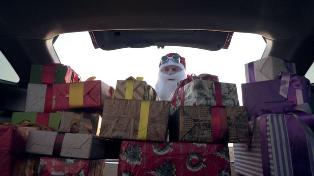 santa claus delivering gifts. gifts from santa. delivery service. deliveryman loads boxes. gift boxes in car. beautifully wrapped parcels. view from inside the car. donation, charity or delivery concept. High quality photo