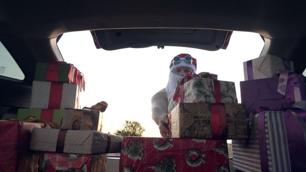 santa claus delivering gifts. gifts from santa. delivery service. deliveryman loads boxes. gift boxes in car. beautifully wrapped parcels. view from inside the car. donation, charity or delivery concept. High quality photo