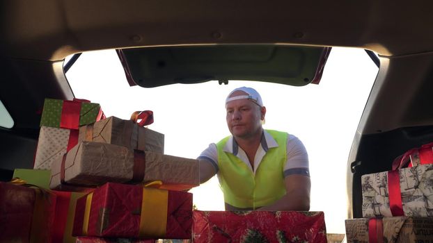 delivery service. deliveryman loads boxes. gift boxes in car. beautifully wrapped parcels. view from inside the car. donation, charity or delivery concept. High quality photo