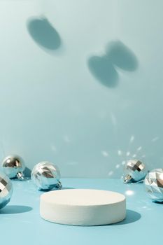 A minimalistic scene of a podium with christmas decorative balls on a light blue background. Catwalk for the presentation of products and cosmetics. Showcase with a stage for products, mockup design, seasonal