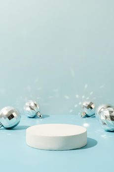 A minimalistic scene of a podium with christmas decorative balls on a light blue background. Catwalk for the presentation of products and cosmetics. Showcase with a stage for products, mockup design, seasonal