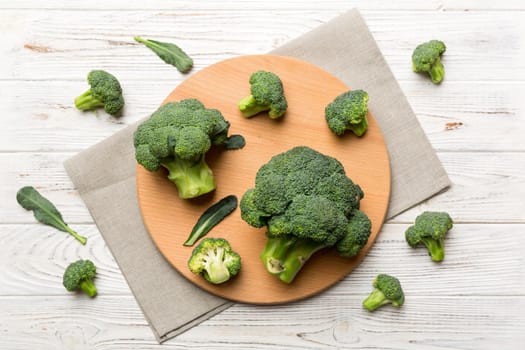 fresh green broccoli on wooden cutting board with knife. Broccoli cabbage leaves. light background. Flat lay.