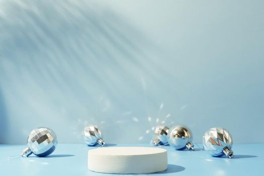 A minimalistic scene of a podium with christmas decorative balls on a light blue background. Catwalk for the presentation of products and cosmetics. Showcase with a stage for products, mockup design, seasonal