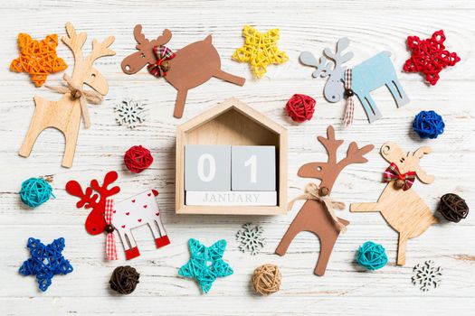 Top view of calendar on Christmas wooden background. The first of January. New Year toys and decorations. Holiday concept.