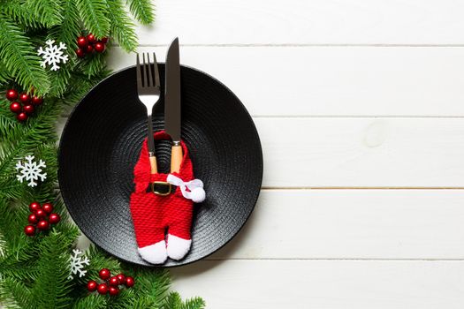 Top view of Christmas dinner on wooden background. Plate, utensil, fir tree and holiday decorations with copy space. New Year time concept.