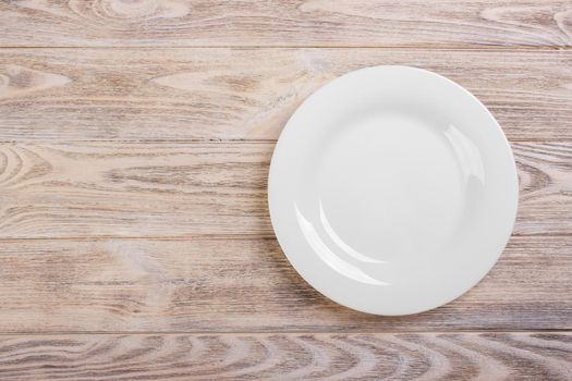 Empty white plate on wooden table. Template for your design.