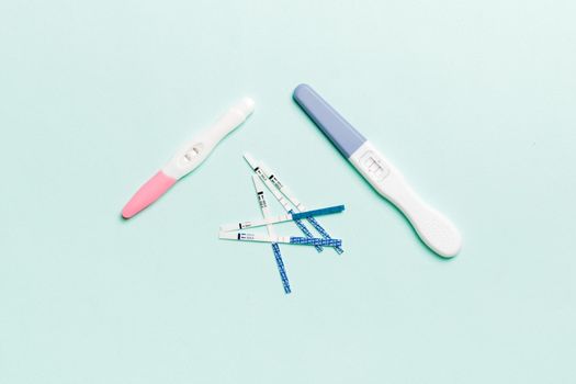 Colored Pregnancy test on colored background, top view with copy space.