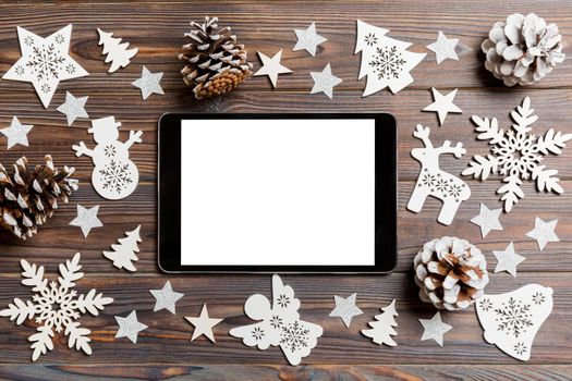 Top view of tablet on holiday wooden background. New Year decorations and toys. Christmas concept.