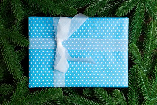 Top view of festive gift box decorated with green fir tree branches. Christmas time with copy space.