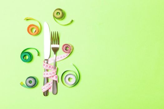 Knife and fork wrapped in tape measure on blue background