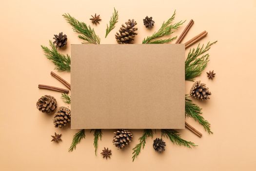 Flat lay Christmas composition. square Paper blank, pine tree branches, christmas decorations on Colored background. Top view, copy space for text.