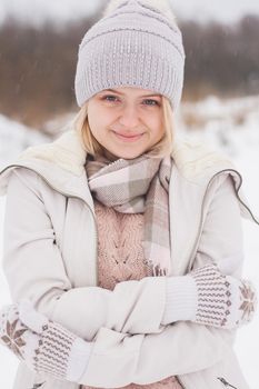 A blonde girl in winter clothes, walking on a snowy steppe. Smiling woman in light clothes in winter in the snow.