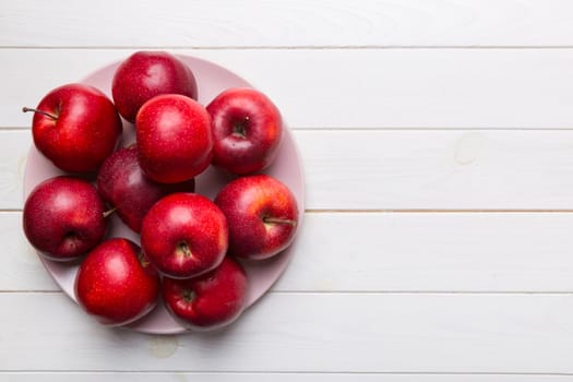 juicy red apples in a bowl or plate on the table top view. Copy space.