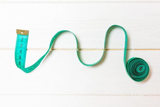 Creative idea of spiral tape measure on wooden background. Sewing concept.