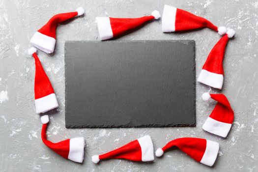 Festive set of plate decorated with Santa Claus hat on cement background. Top view christmas dinner concept.