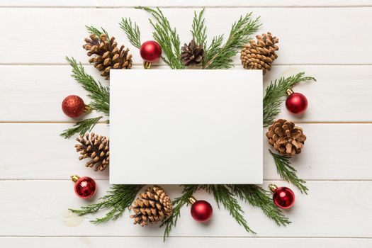 Flat lay Christmas composition. square Paper blank, pine tree branches, christmas decorations on Colored background. Top view, copy space for text.