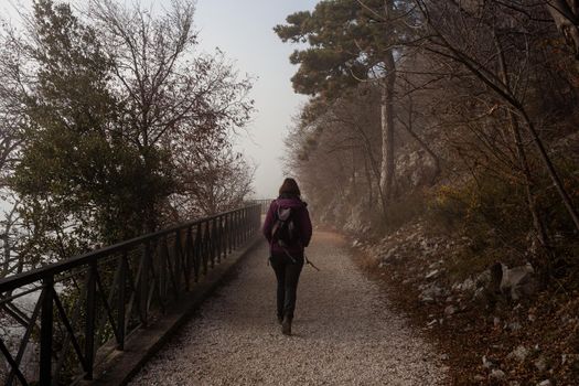 Back view of a Woman walking alone on rural misty path called Napoleonica, Trieste