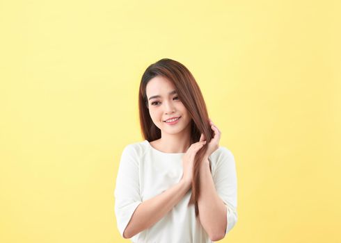 Beauty woman touch her long hair isolated on yellow background, asian beauty 