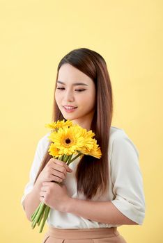 Asian lady holding a bunch of flower standing against a wall