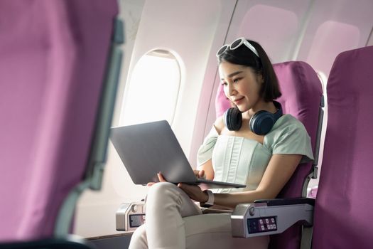 Attractive asian woman passenger of airplane using laptop computer and wifi on board. tourism traveler concept