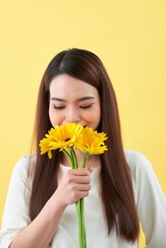 young woman smelling sunflowers on the yellow background