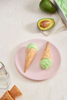 Green avocado ice cream scoops in wafle cones on white background. Copy space