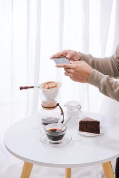 Handsome asian taking photo of chocolate cake and milk at coffee shop. Dessert or food photography hobby. Smartphone or mobile phone photography habit concept. 