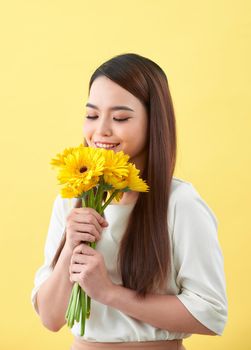young woman smelling sunflowers on the yellow background
