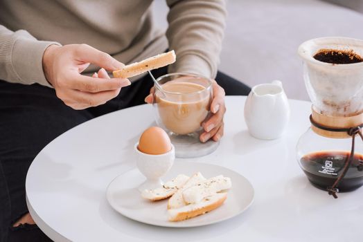 Fresh delicious breakfast with soft boiled egg, crispy toasts and cup coffee in living room