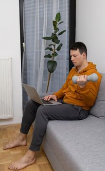 young man exercising at home sitting on couch. High quality photo