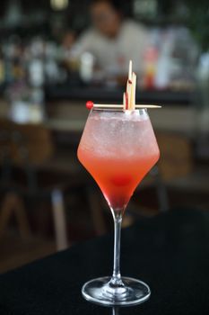 Pink Cocktail glass with ice at a bar counter