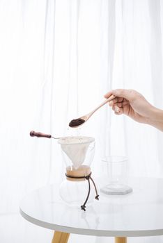 fill grind coffee in filter with wooden spoon