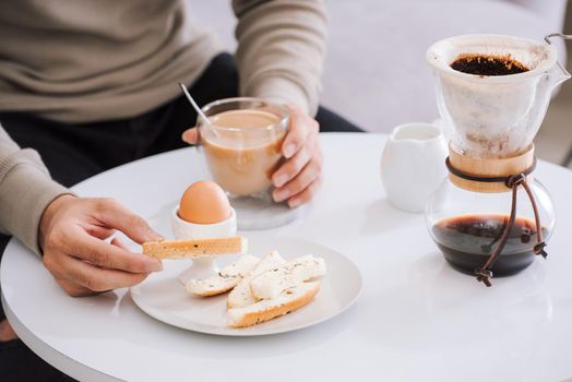 Fresh delicious breakfast with soft boiled egg, crispy toasts and cup coffee in living room