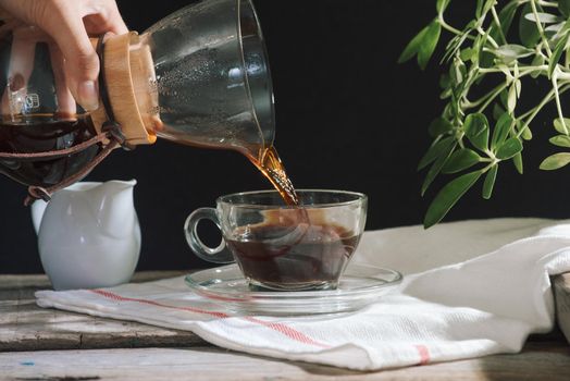 Man pouring cold brew coffee into glass on table