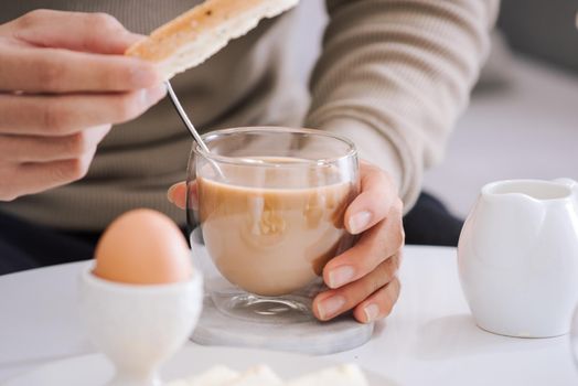 Fresh delicious breakfast with soft boiled egg, crispy toasts and cup coffee in living room