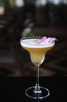 Yellow Cocktail glass with ice at a bar counter