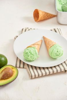 Green avocado ice cream scoops in wafle cones on white background. Copy space