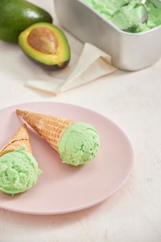 Green avocado ice cream scoops in wafle cones on white background. Copy space