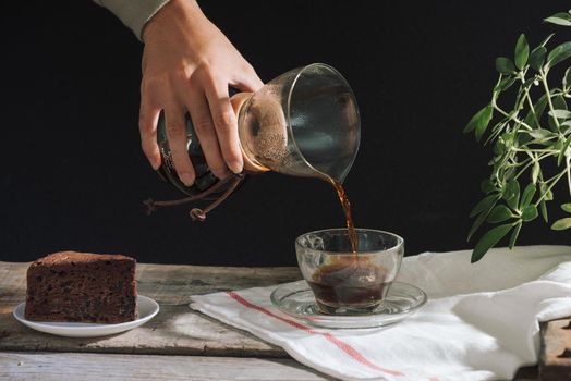 Man pouring cold brew coffee into glass on table