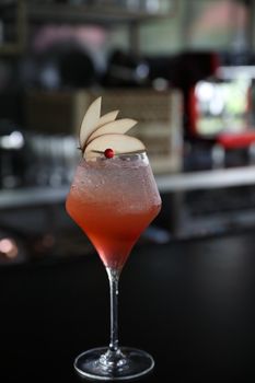 Pink Cocktail glass with ice at a bar counter