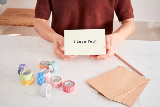 hands holding greeting card with phrase letters "i love you" prepared for sweetheart