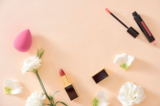 Red lipstick make up and flowers arranged on a pastel purple background with empty space at side