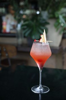 Pink Cocktail glass with ice at a bar counter