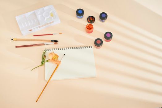 Set of watercolor paint, art brushes and paper on a desk 