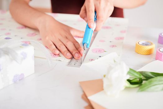 Detail of woman hands packing some presents with gift paper