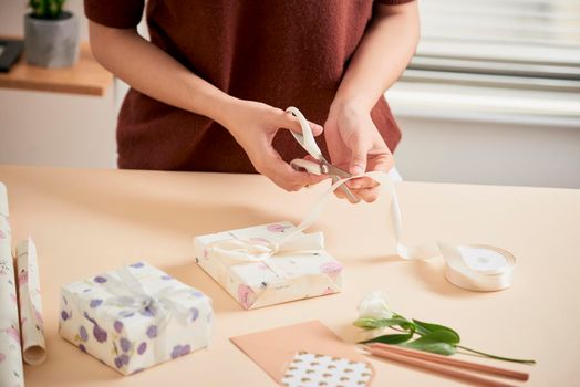 Detail of woman hands packing some presents with gift paper