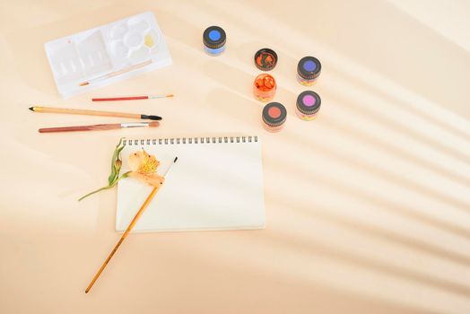 Set of watercolor paint, art brushes and paper on a desk 